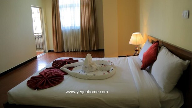 A hotel room with a neatly made bed, a lamp on the nightstand, and a view of the outside through the window. - Bruhway Hotel (Addis Ababa)