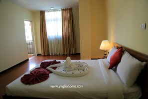 A hotel room with a neatly made bed, a lamp on the nightstand, and a view of the outside through the window. - Bruhway Hotel (Addis Ababa)