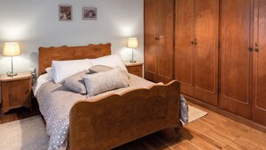A bedroom with a wooden bed, two bedside tables with lamps, a wardrobe, and two framed pictures on the wall. - Classy & Spacious Flat near Marina of Patra (Patras)