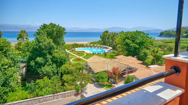 Resort com piscina, praia e montanhas ao fundo.
