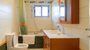 Un baño con inodoro, lavamanos, ducha y ventana.