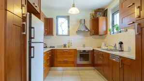 Una cocina con armarios de madera, un refrigerador de acero inoxidable, un horno y una ventana con vistas.