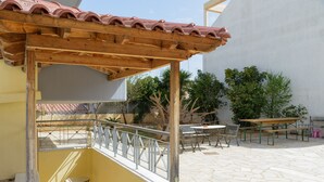 Un patio al aire libre techado con una pérgola de madera, una mesa pequeña y un banco.