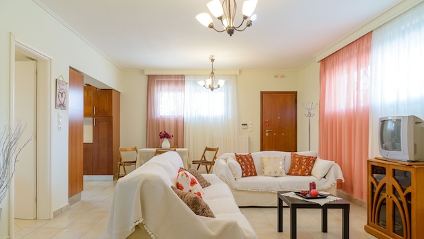 Una sala de estar con dos sofás, una mesita de centro, un televisor y un mueble de madera.