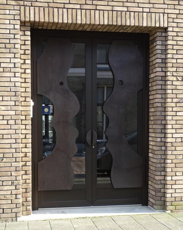 A double door with a unique abstract design, set in a brick wall. - Arthouse B&B Dordrecht (Dordrecht)