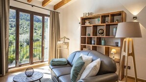 A living room with a leather sofa, a small round table, a bookshelf, and a lamp. - Luxurious finca with large pool in a unique location (Andratx)