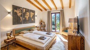 A bedroom with two beds, wooden beams, a world map artwork, a balcony with a view, and a TV. - Luxurious finca with large pool in a unique location (Andratx)