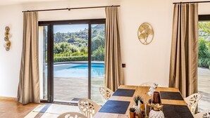A dining area with a table set for four, a view of a pool and greenery outside, and a sliding glass door. - Luxurious finca with large pool in a unique location (Andratx)