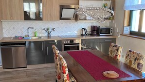 Eine moderne Küche mit Holzschränken, Edelstahlgeräten und einem Essbereich mit floralen Stühlen und einem Holztisch.