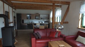 Ein gemütliches Wohnzimmer mit einem roten Sofa, einem Holztisch und einem schwarzen Kaminofen.