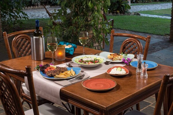 A dining table set with plates of food, a bottle of wine, and a candle.