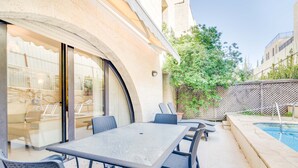 Un patio exterior con piscina, una mesa y sillas.