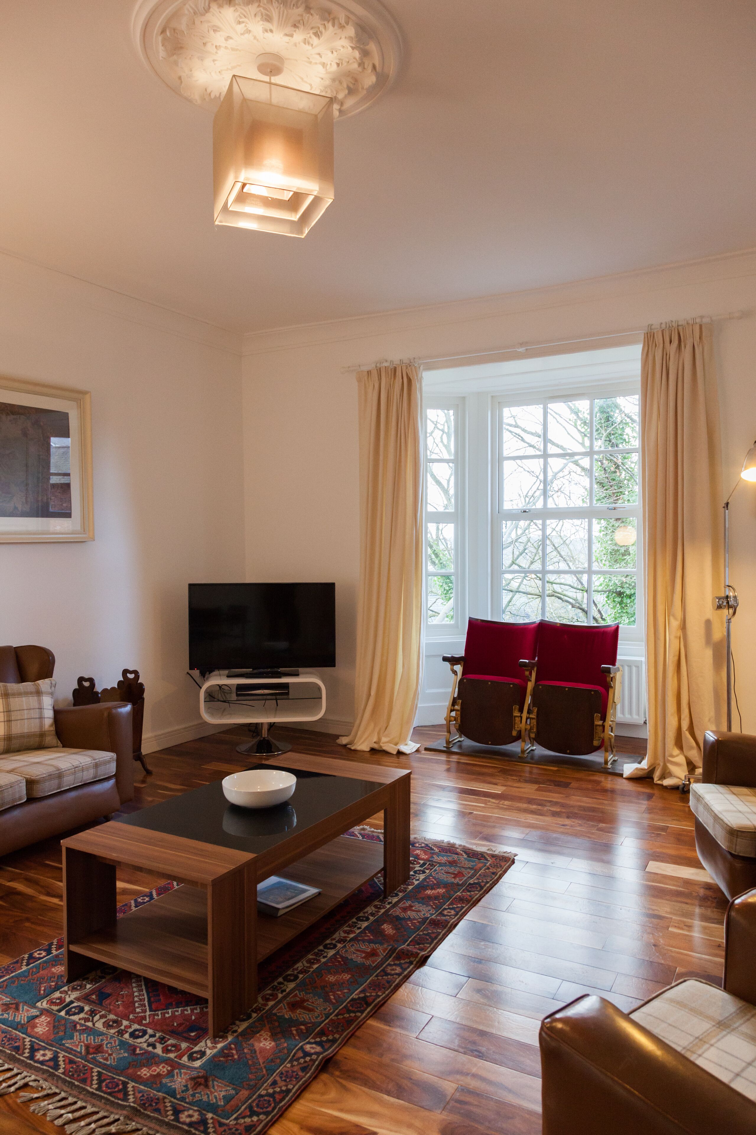 A living room with a flat-screen TV, wooden coffee table, and a patterned rug.