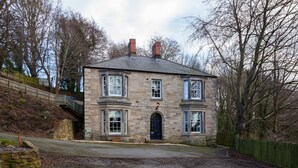 A stone building with a black door, multiple windows, and a chimney. - Apartment 3 The Grove (Durham)