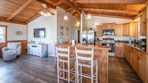 A spacious kitchen with wooden cabinets, a central island, and a ceiling fan. - 5377- Memorial Blvd. - Family-Friendly KDH Retreat Near the Beach (Kill Devil Hills)
