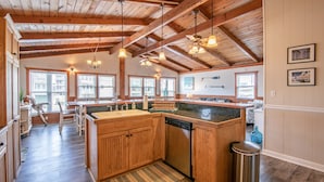 A spacious kitchen with wooden cabinets, a large island, and a ceiling fan. - 5377- Memorial Blvd. - Family-Friendly KDH Retreat Near the Beach (Kill Devil Hills)