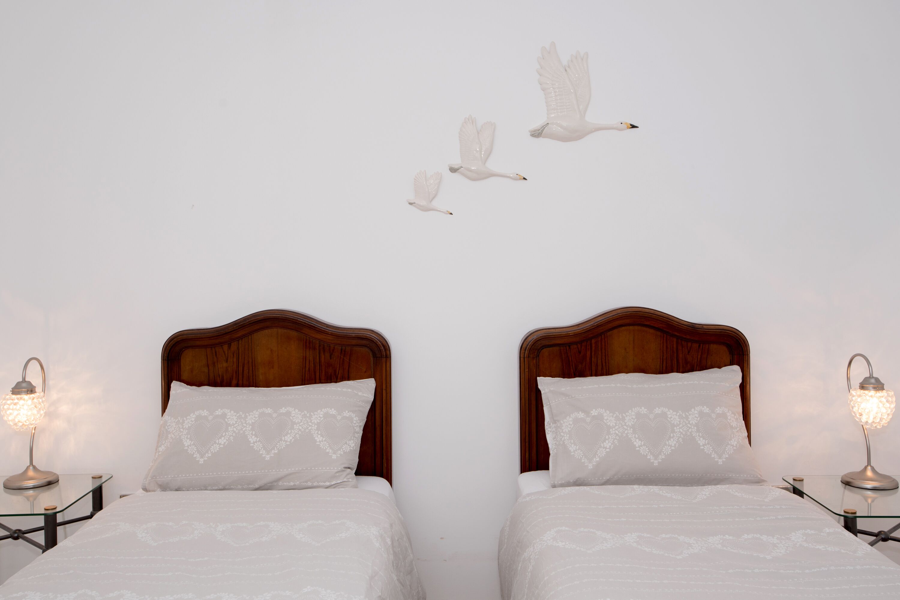 A double bed with heart-patterned pillows and a nightstand with a lamp.