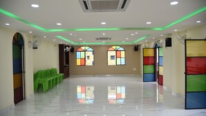 A spacious hall with a polished marble floor, green chairs, and colorful stained glass windows.