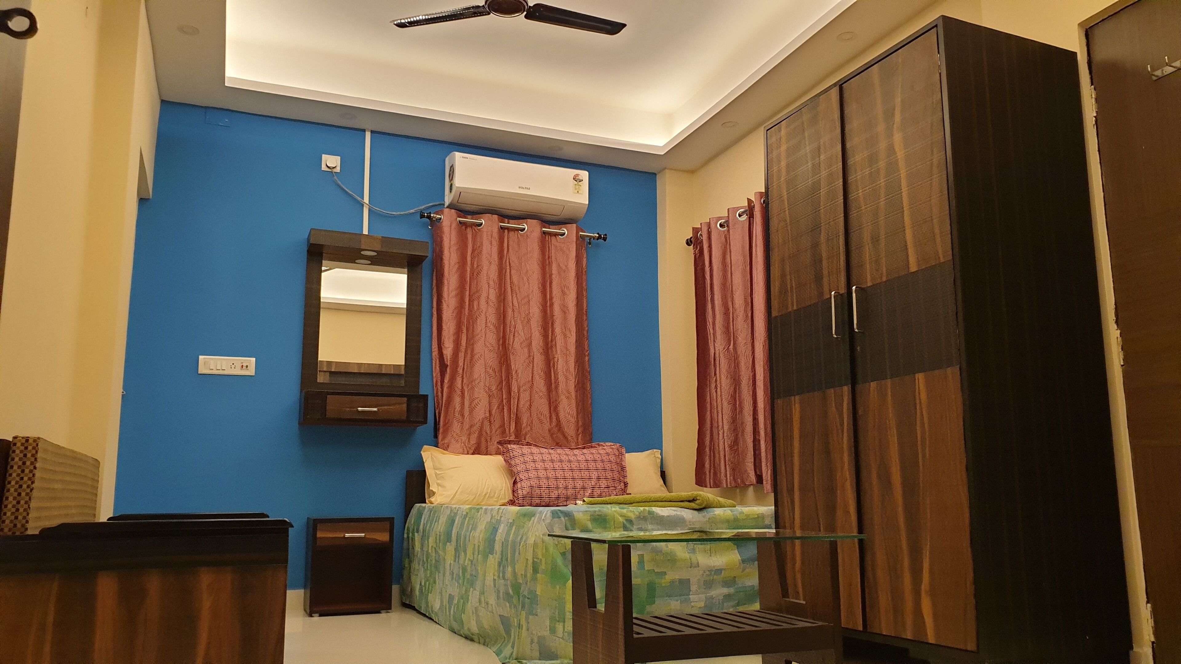 A bedroom with a bed, a mirror, a wardrobe, and an air conditioning unit.