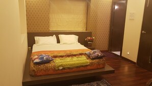 A bed with a patterned bedspread, two pillows, and a vase with flowers on a bedside table.