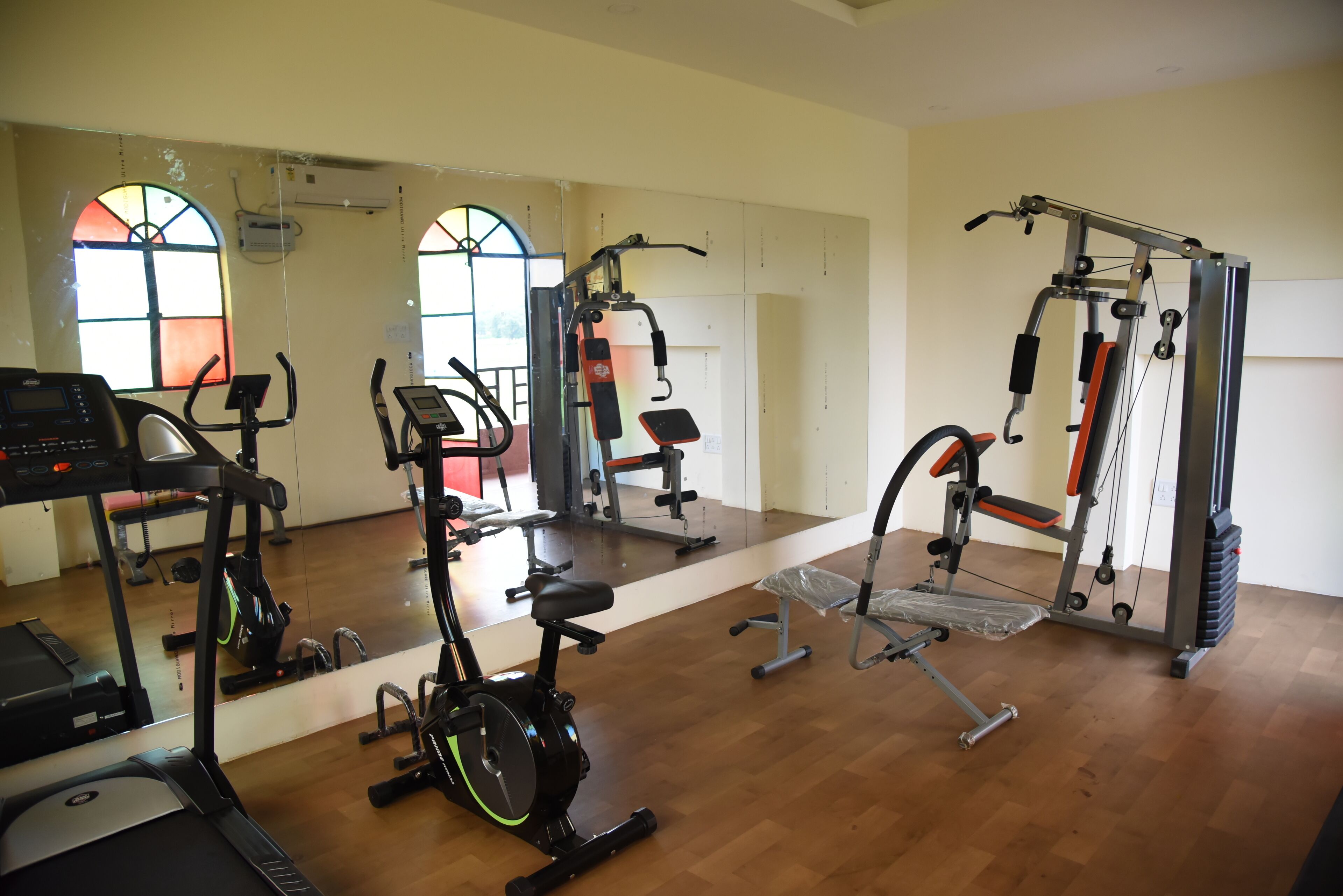 Ett gym med konditionsmaskiner, styrketräningsutrustning och speglar.