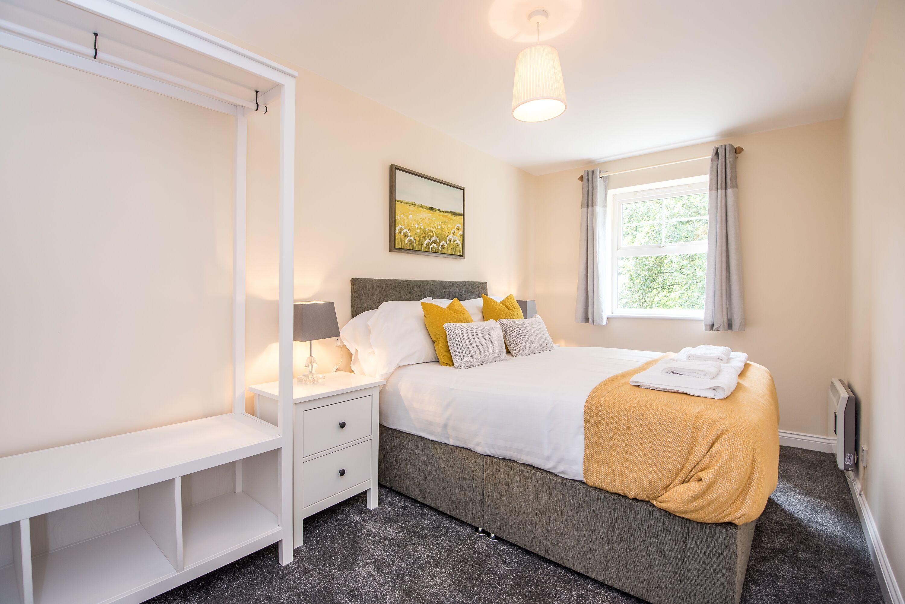 Een slaapkamer met een bed, nachtkastje en een kledingkast.
