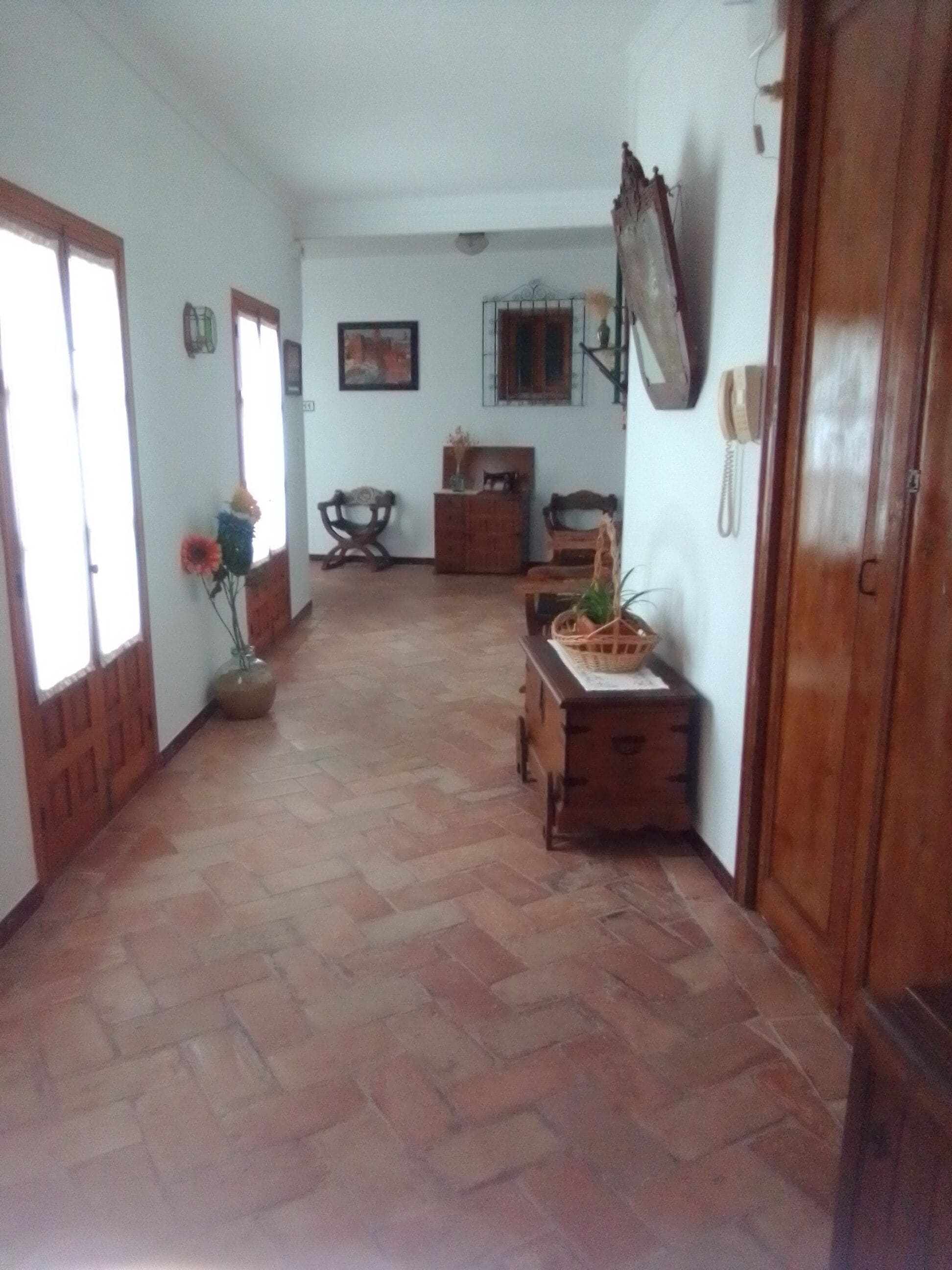 A hallway with a tiled floor, wooden furniture, and a door on the right.