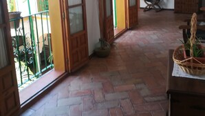 Ruime kamer met betegelde vloer, houten deuren, een bankje, een tafeltje en een potplant.