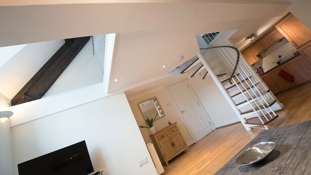 A modern kitchen with wooden cabinets, a built-in stove, and a dining area with a table and chairs. - St Andrews Court (Durham)