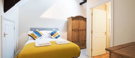 A bedroom with a bed, a wooden wardrobe, and a door.