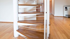 A spiral staircase with wooden steps and white railings, leading to an upper landing. - St Andrews Court (Durham)