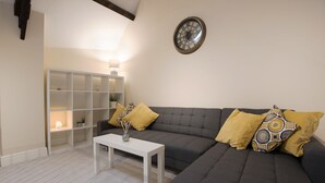 A living room with a grey sofa, white coffee table, and a bookshelf. - St Andrews Court (Durham)