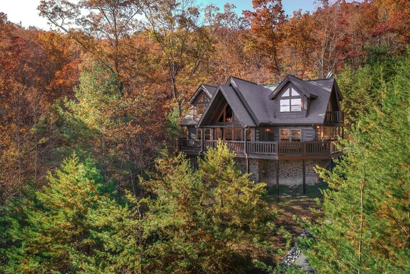 A cabin with a stone foundation, wooden upper structure, and a balcony. - Tree Top. Beautiful Mountain View, Pool table, Hot Tub, Arcade Game, Private Mountain Setting (Sevierville)
