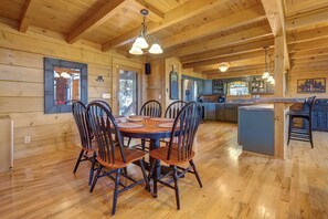 A wooden cabin interior with a dining area, kitchen, and a large window. - Tree Top. Beautiful Mountain View, Pool table, Hot Tub, Arcade Game, Private Mountain Setting (Sevierville)