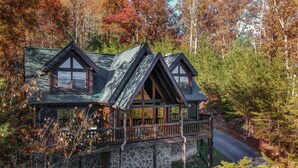 A cabin with a stone foundation, wooden deck, and two pitched roofs. - Tree Top. Beautiful Mountain View, Pool table, Hot Tub, Arcade Game, Private Mountain Setting (Sevierville)