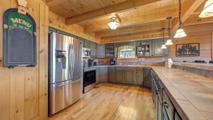 A spacious kitchen with wooden cabinets, stainless steel appliances, and pendant lighting. - Tree Top. Beautiful Mountain View, Pool table, Hot Tub, Arcade Game, Private Mountain Setting (Sevierville)