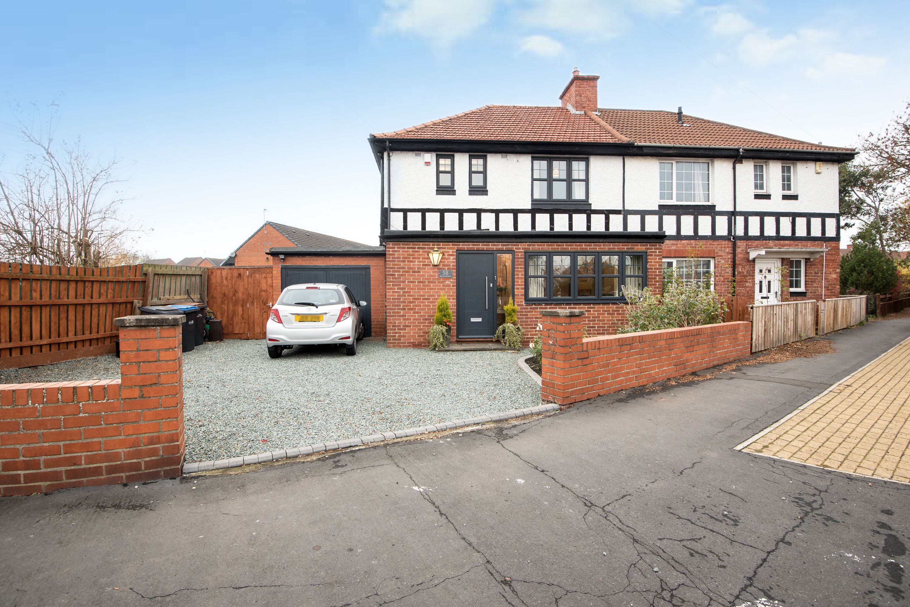 A two-story house with a garage, a driveway, and a small garden area.