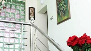 A staircase with a metal railing, a window with green-tinted glass, and a painting on the wall. - Kelin Court Hotel (Lagos)