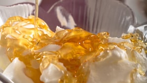 A glass bowl with a white substance and a golden liquid being poured into it. - Ali Pasha Hotel (Ioannina)