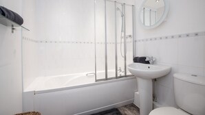 A modern bathroom with a glass-enclosed shower, a white bathtub, a pedestal sink, and a toilet.