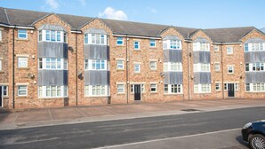 A row of brick townhouses with large windows, a central entrance, and a paved driveway.