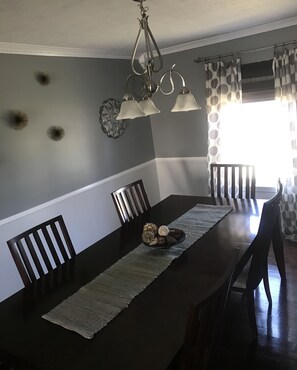 Enjoy meals in this dining area with a table for four, a stylish chandelier, and a decorative wall piece.