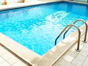 A rectangular swimming pool with clear blue water and a metal ladder on the right side. - Rush Hotel (Lagos)