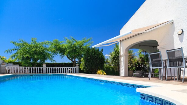 A clear blue swimming pool with a white deck, a covered seating area, and a white fence. - Spacious villa with private pool and free wifi, sleeps 12 - VILLA NOSTRA (Cambrils)