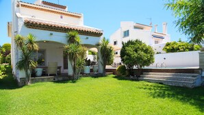 A white building with a tiled roof, a covered patio area with outdoor furniture, and a swimming pool. - Spacious villa with private pool and free wifi, sleeps 12 - VILLA NOSTRA (Cambrils)