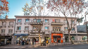 A multi-story building with various shops on the ground floor, including a real estate agency and a pizza place. - Wine Inn Cascais (Cascais)