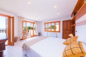 A bedroom with a large bed, wooden wardrobe, and a sliding glass door leading to an outdoor area.