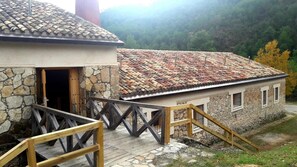 A stone building with a tiled roof, wooden stairs, and a wooden railing. - Albergue Tejadillos - Hostel (Cuenca)