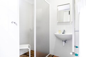 A bathroom with a white sink, mirror, and shower area. - Albergue Tejadillos - Hostel (Cuenca)