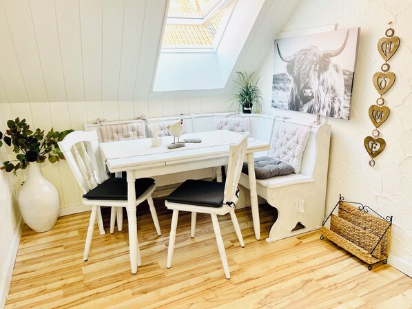 A cozy dining area with a white table and chairs, a bench, and a wall-mounted decorative piece. - Spend the night on the "Old Hoop" (Leese)
